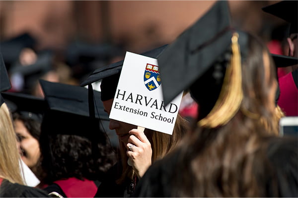 graduation with someone holding harvard extension school sign